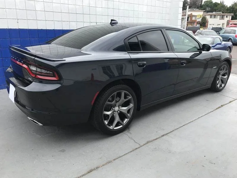 The same Dodge Charger R/T finished and parked in the shop yard against the blue tiled wall, with the rear quarter, bumper and tail light back to a straight factory line